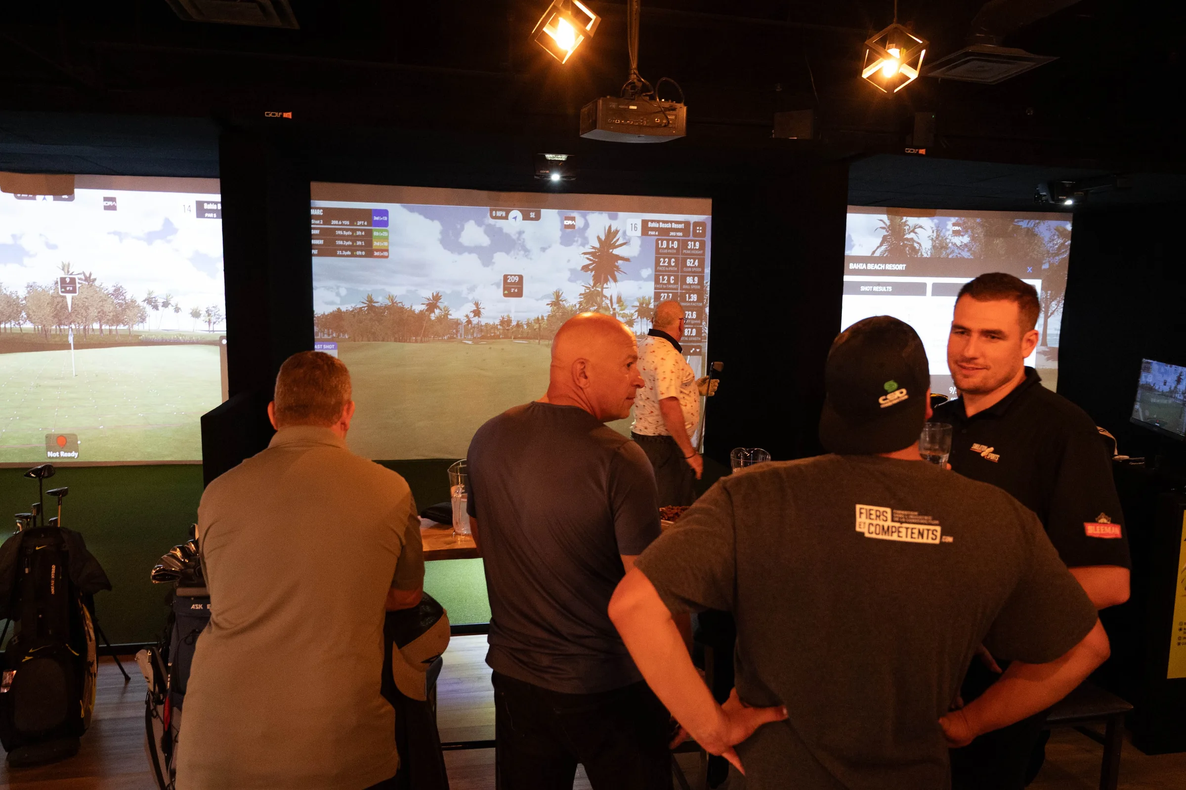 Des golfeurs discutent devant les écrans de Simulation Sports Laurentides, un soir de ligue.